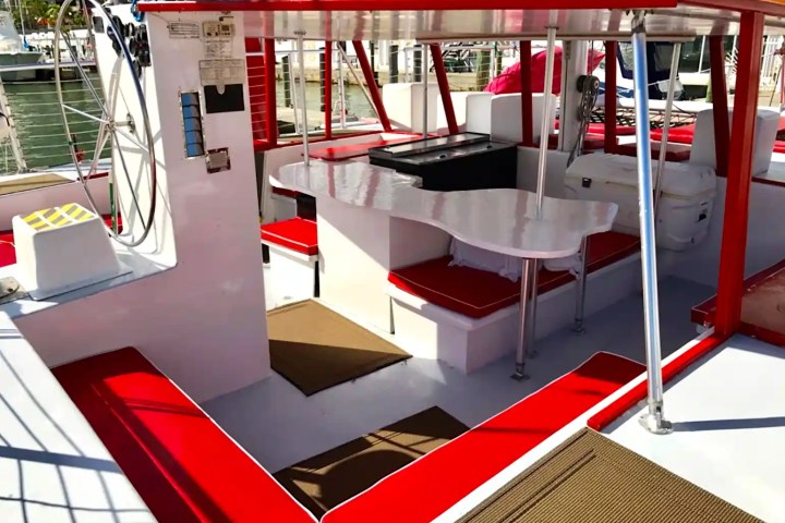 Boat interior with red and white seating, steering wheel, and canopy.