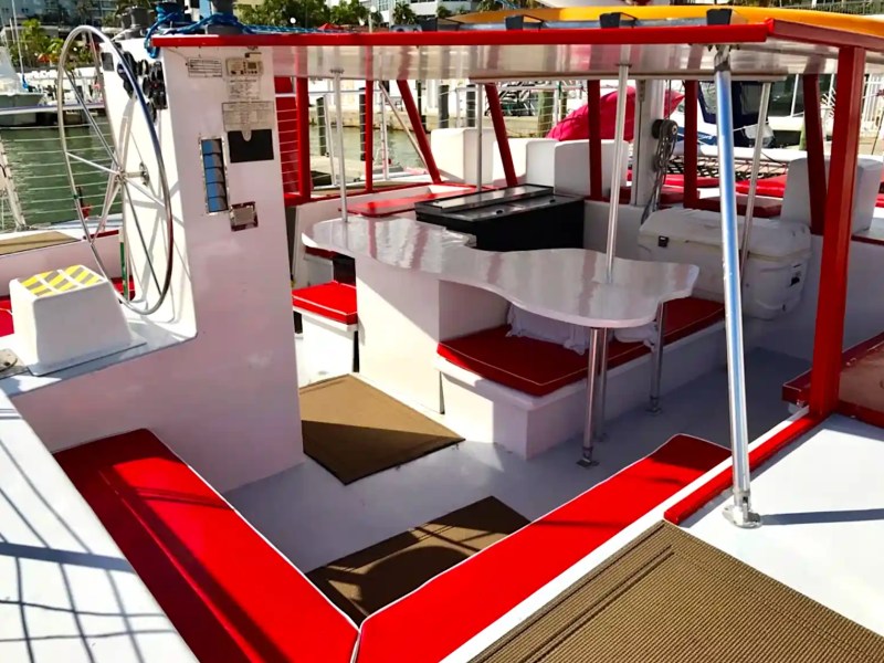 Boat interior with red and white seating, steering wheel, and canopy.