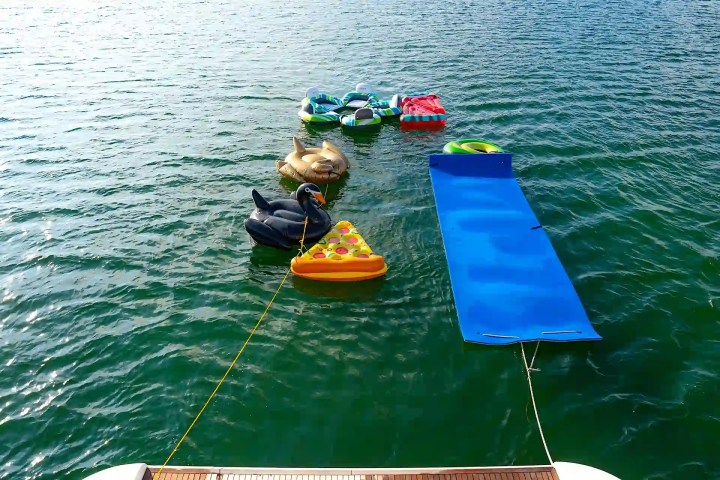 Inflatable pool toys and a blue float on water near a boat.
