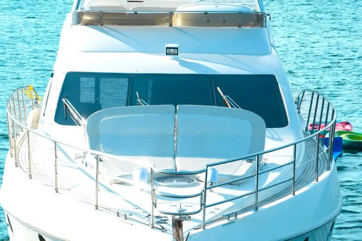White yacht on blue water with colorful inflatables on the side.