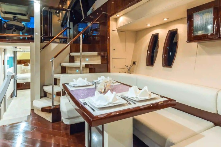 Luxurious yacht interior with a dining table, staircase, and modern decor.