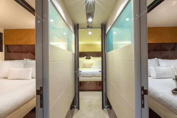 Interior view of a yacht bedroom suite with three beds and modern decor.