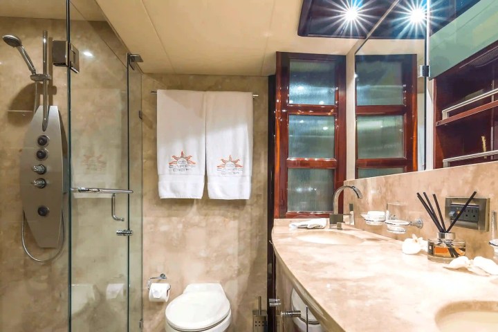 Luxurious bathroom with marble countertop, double sink, glass shower, and decorative mirrors.
