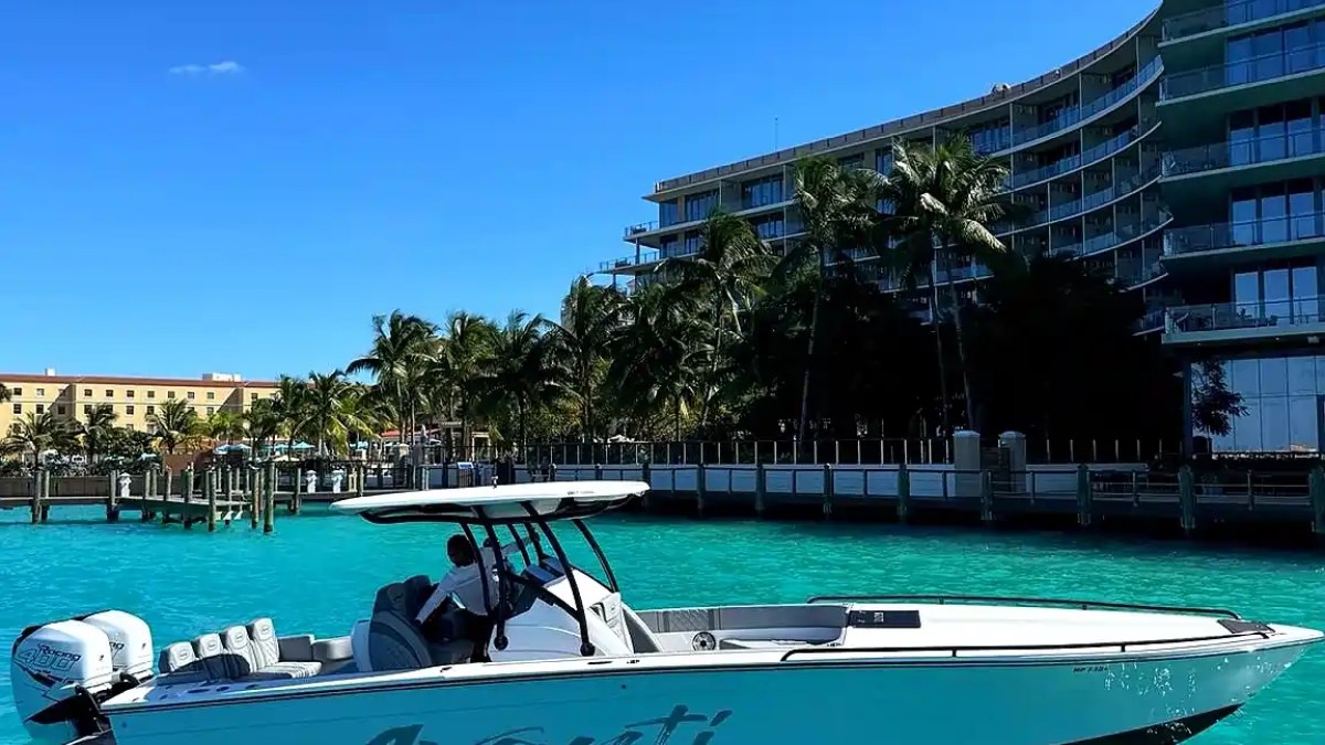 Motorboat named Avanti in turquoise water with buildings and palm trees in the background.