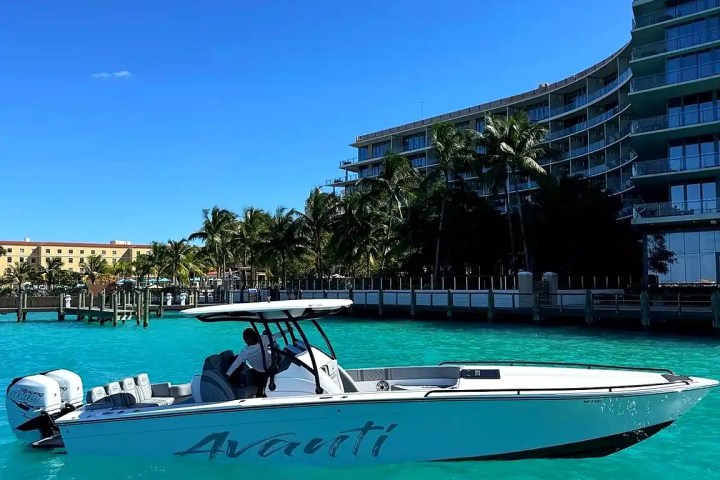 Motorboat named Avanti in turquoise water with buildings and palm trees in the background.