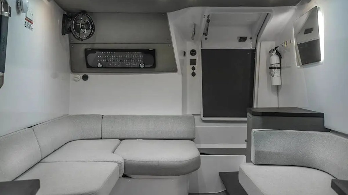 Modern RV interior with gray seating, fan, and fire extinguisher.