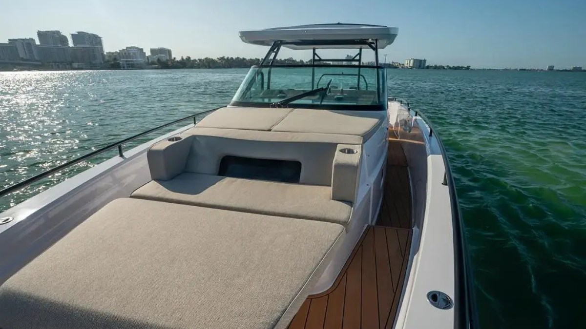 A luxury yacht on a sunny sea with city skyline in the background.