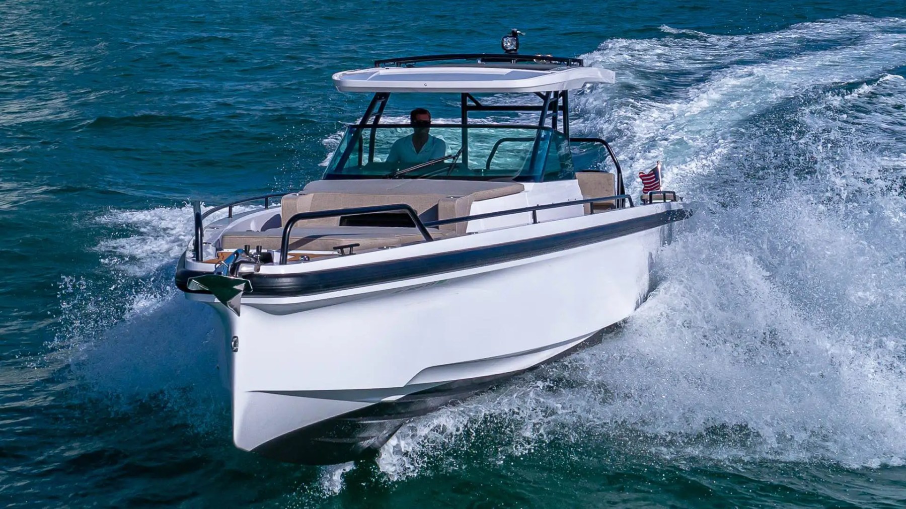 White motorboat with canopy speeding on ocean, creating waves.