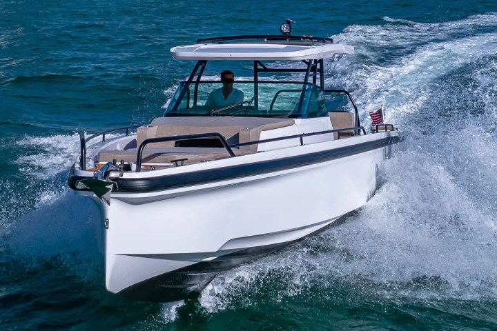White motorboat with canopy speeding on ocean, creating waves.