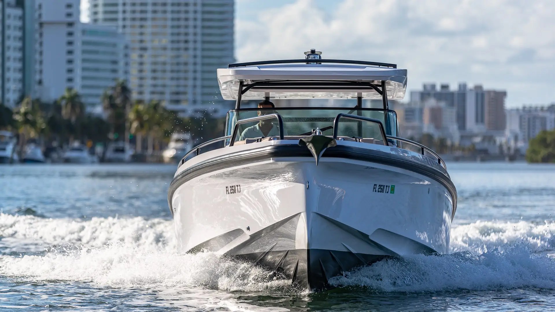 A boat cruising on water with cityscape background and clear sky.