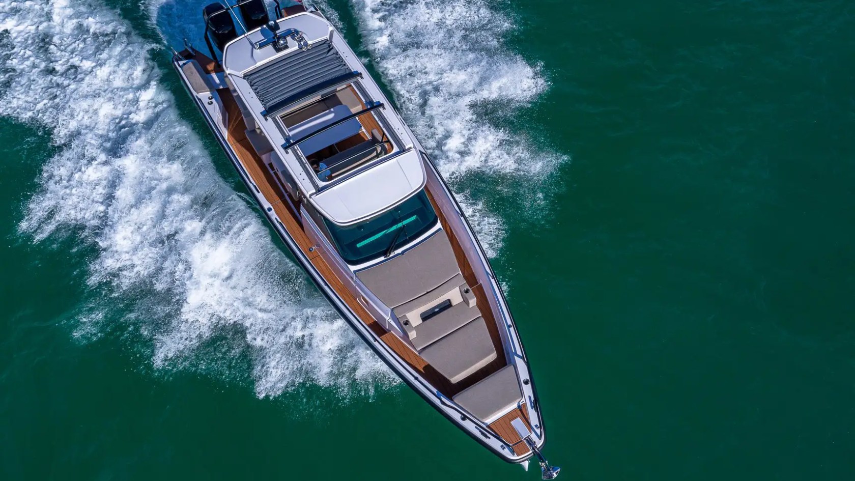 Aerial view of a motor yacht cruising on clear blue water.