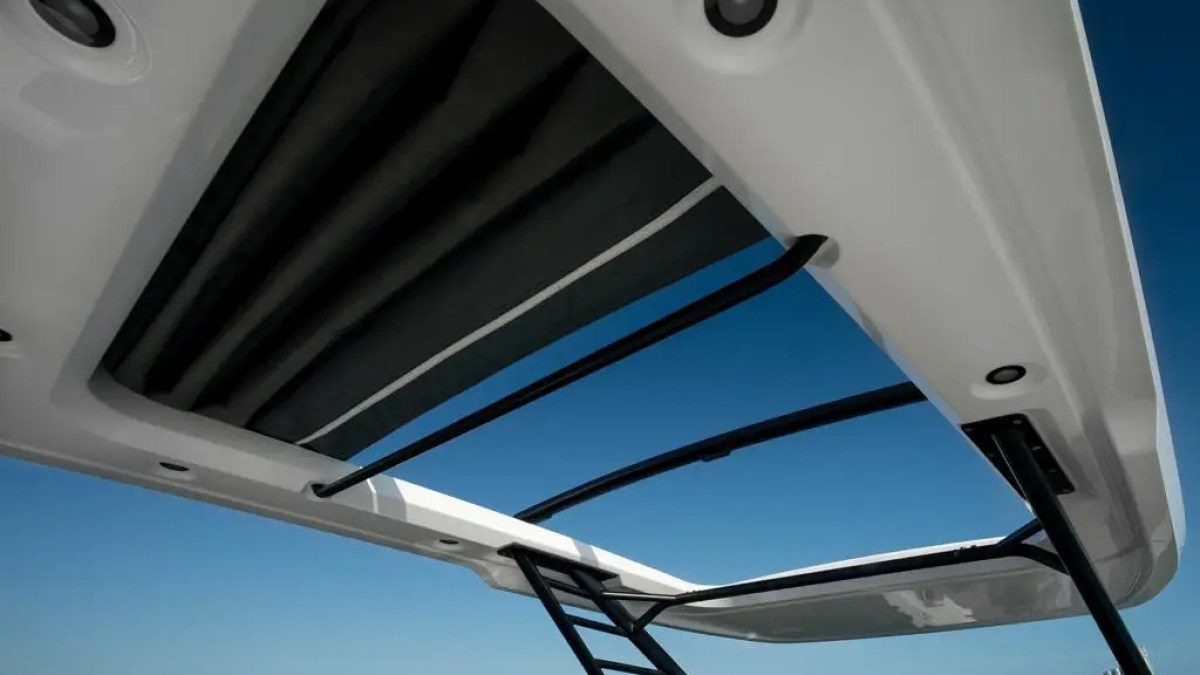 View through a boat's open sunroof with clear sky and buildings on the horizon.