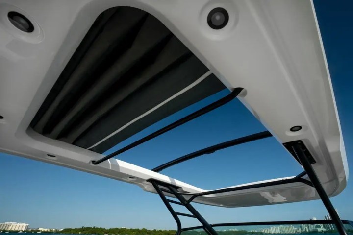 View through a boat's open sunroof with clear sky and buildings on the horizon.