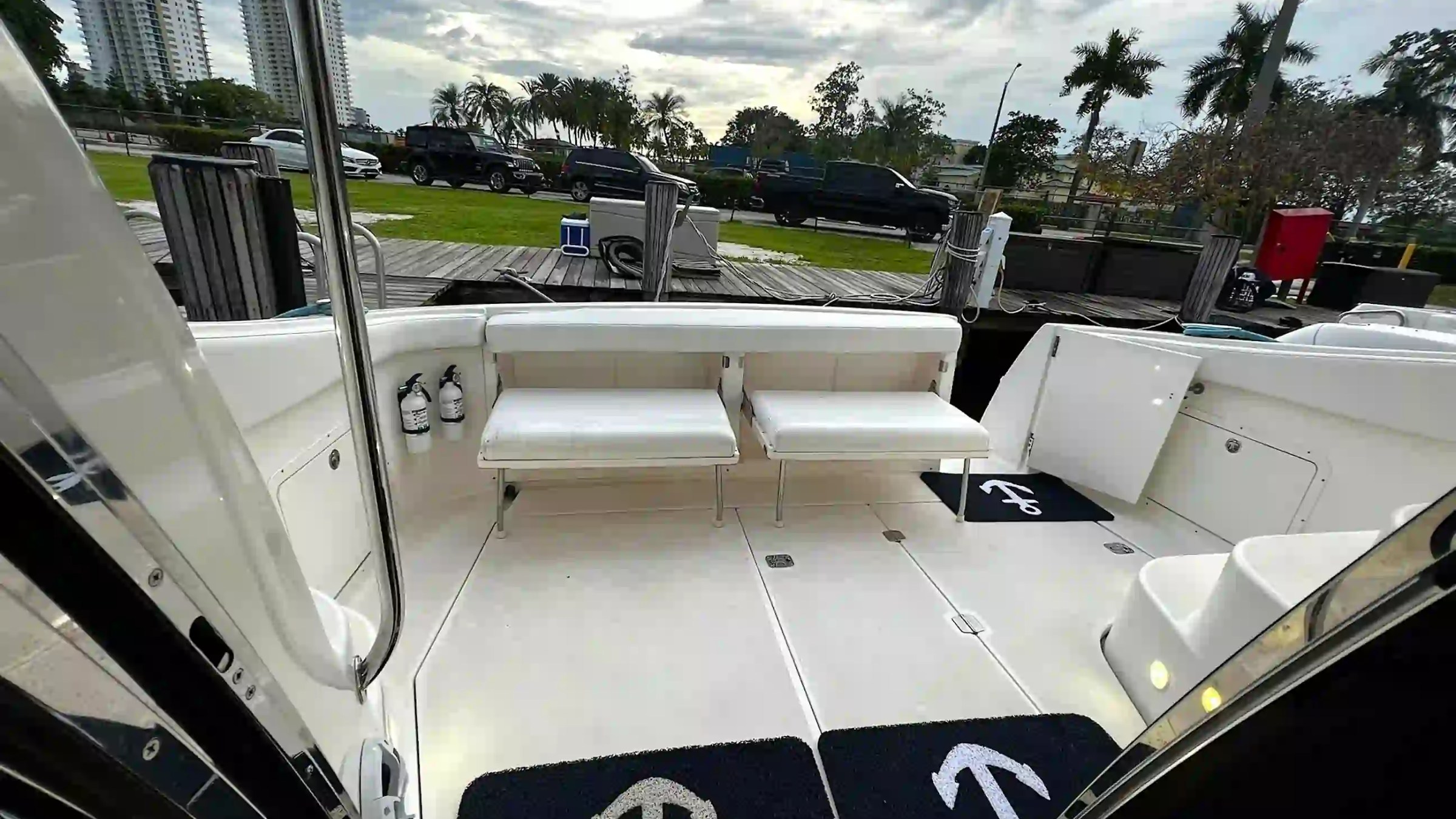 Interior of a boat with white seating, black mats, and fire extinguishers visible.