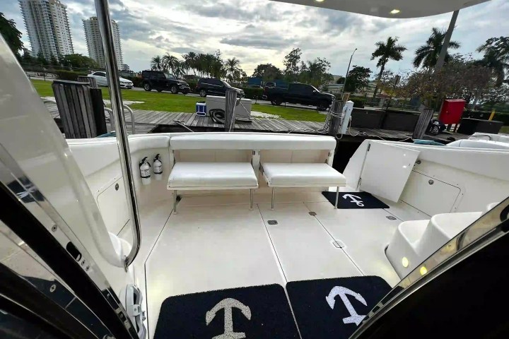 Interior of a boat with white seating, black mats, and fire extinguishers visible.