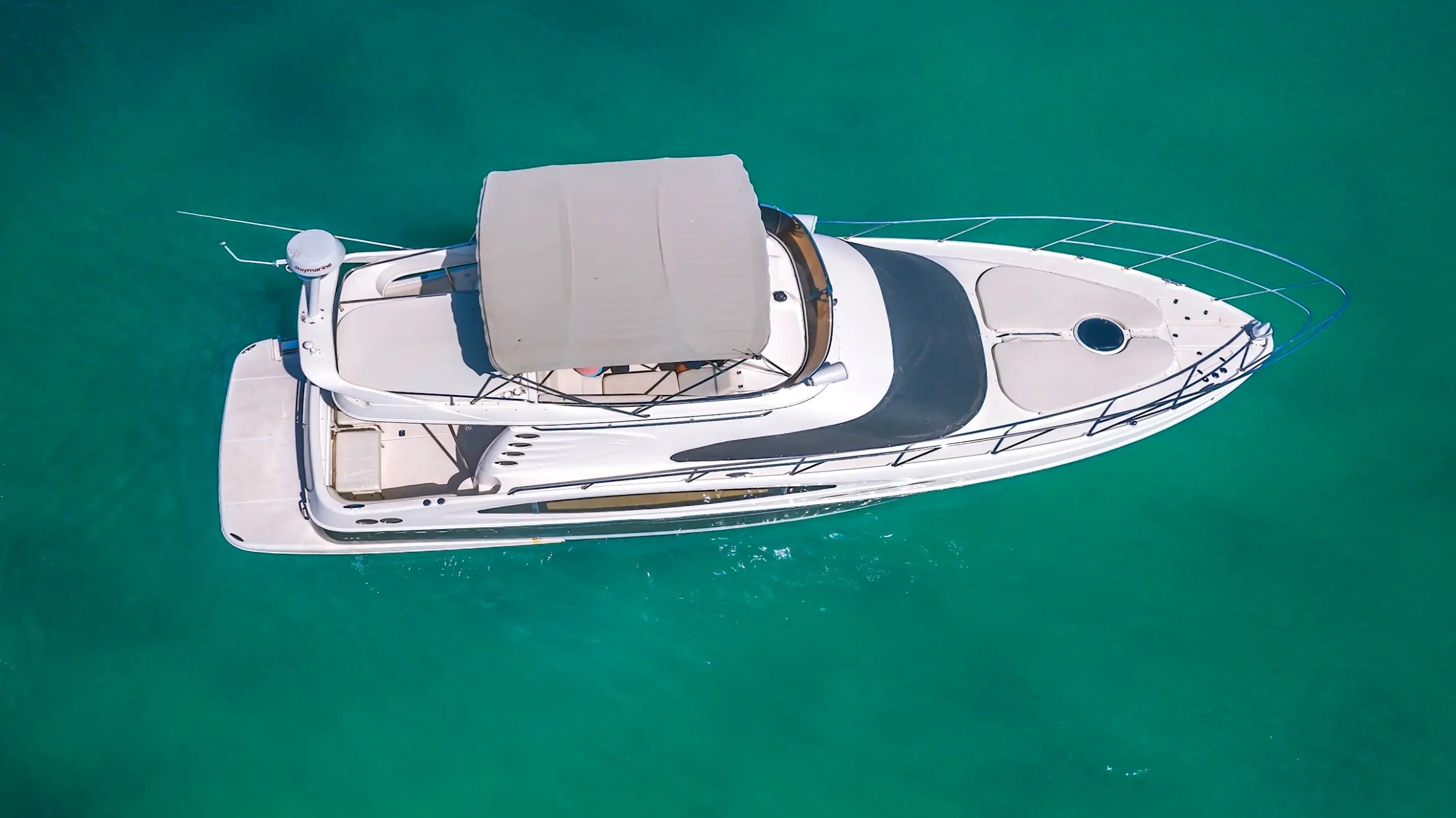 Aerial view of a white yacht on clear turquoise water.