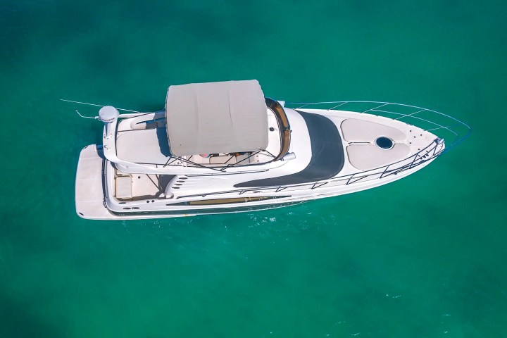 Aerial view of a white yacht on clear turquoise water.