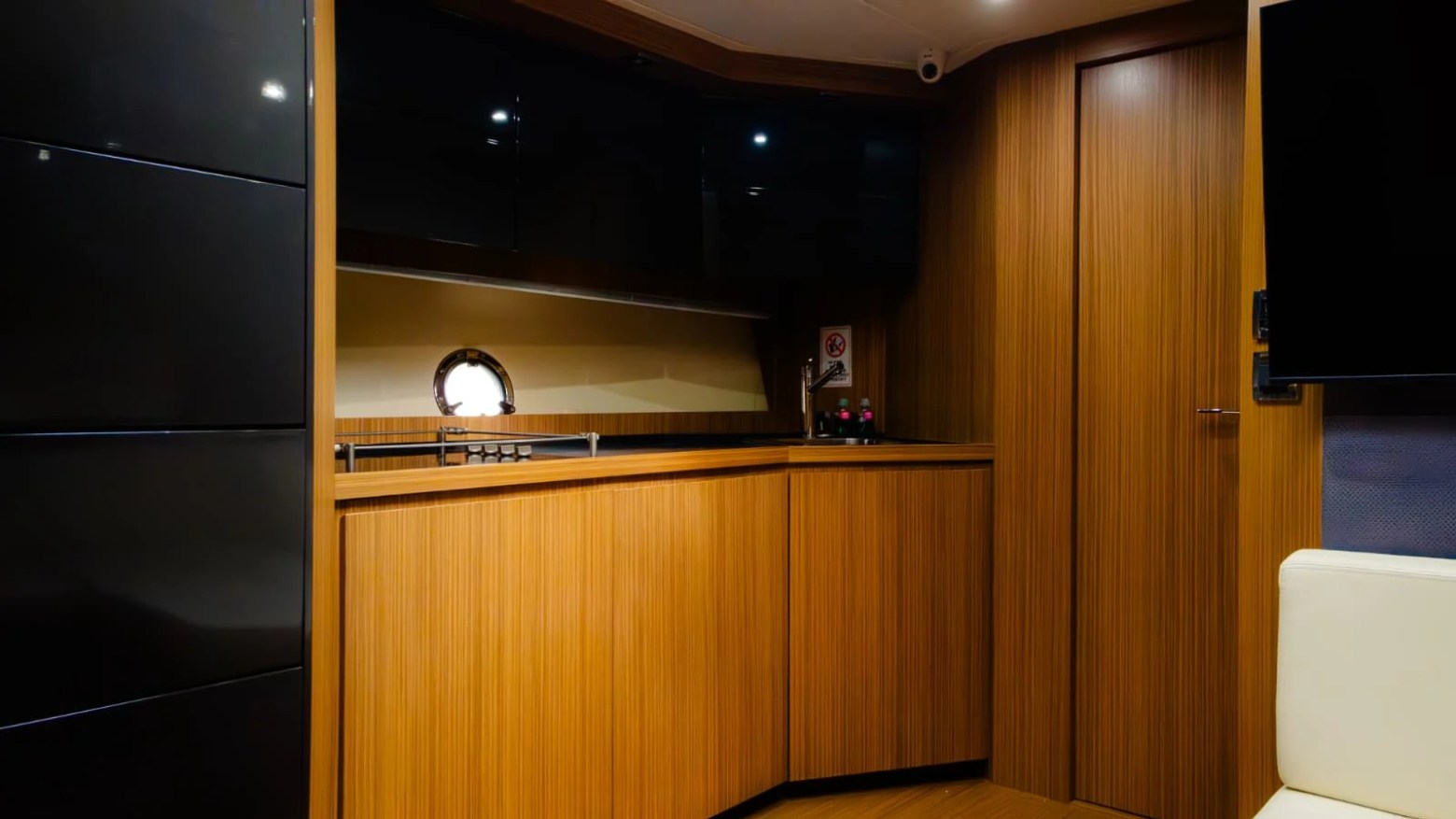 Modern boat interior with wood paneling, small window, and minimalist furnishings.