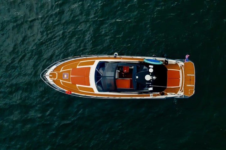 Top view of a modern boat with wooden deck floating on dark water.