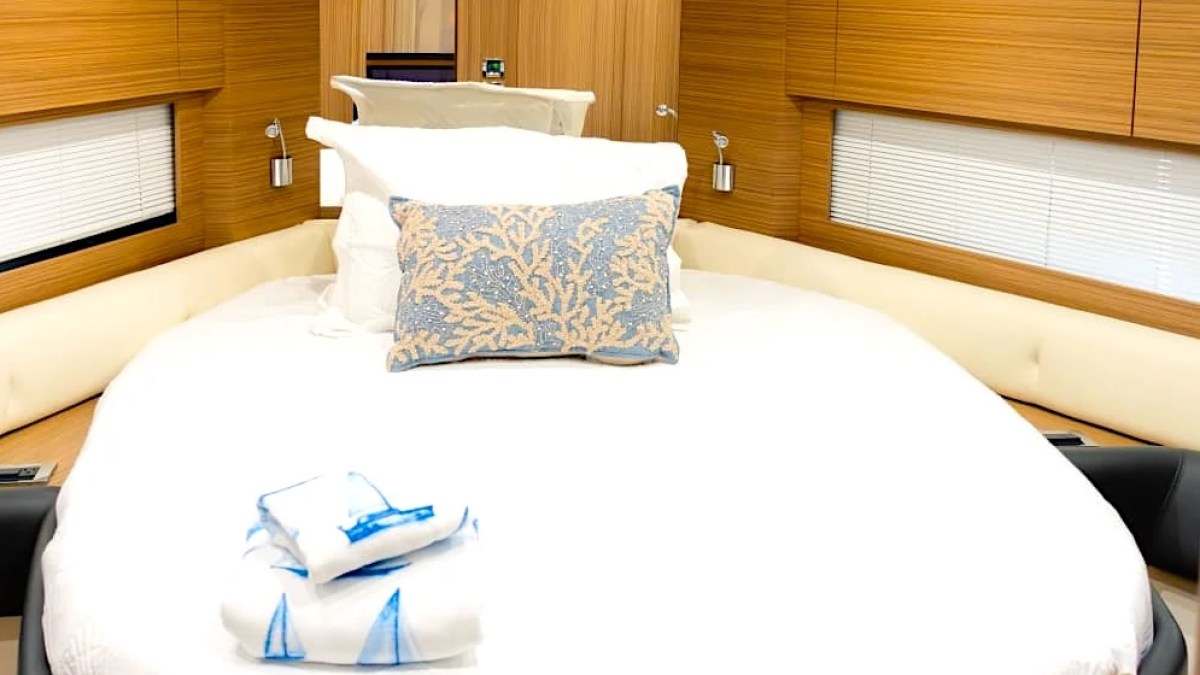 Cozy boat cabin with a bed, decorative pillows, and folded towels.