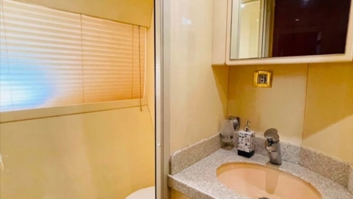 Compact bathroom with sink, mirror, toilet, and window blinds.