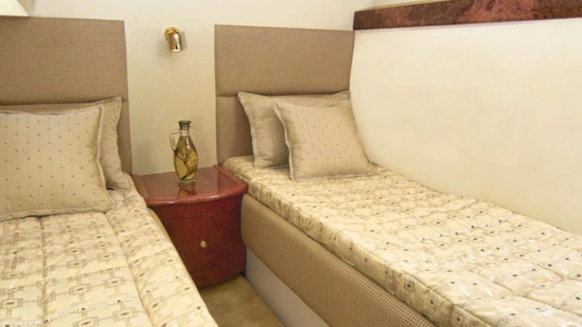 Two twin beds with beige bedding and a shared nightstand in between.