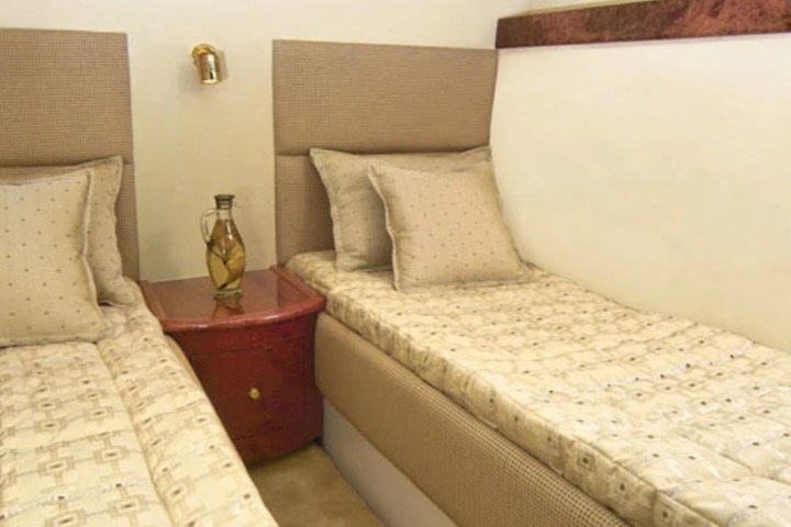 Two twin beds with beige bedding and a shared nightstand in between.