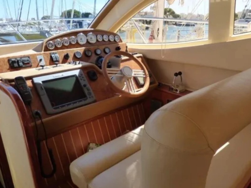 Interior view of a yacht cockpit with steering wheel and control panels.