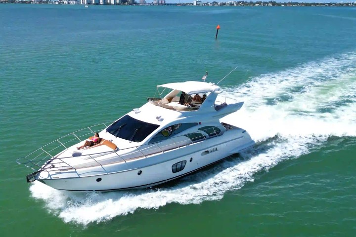 Luxury yacht cruising on a clear blue ocean near a city skyline.