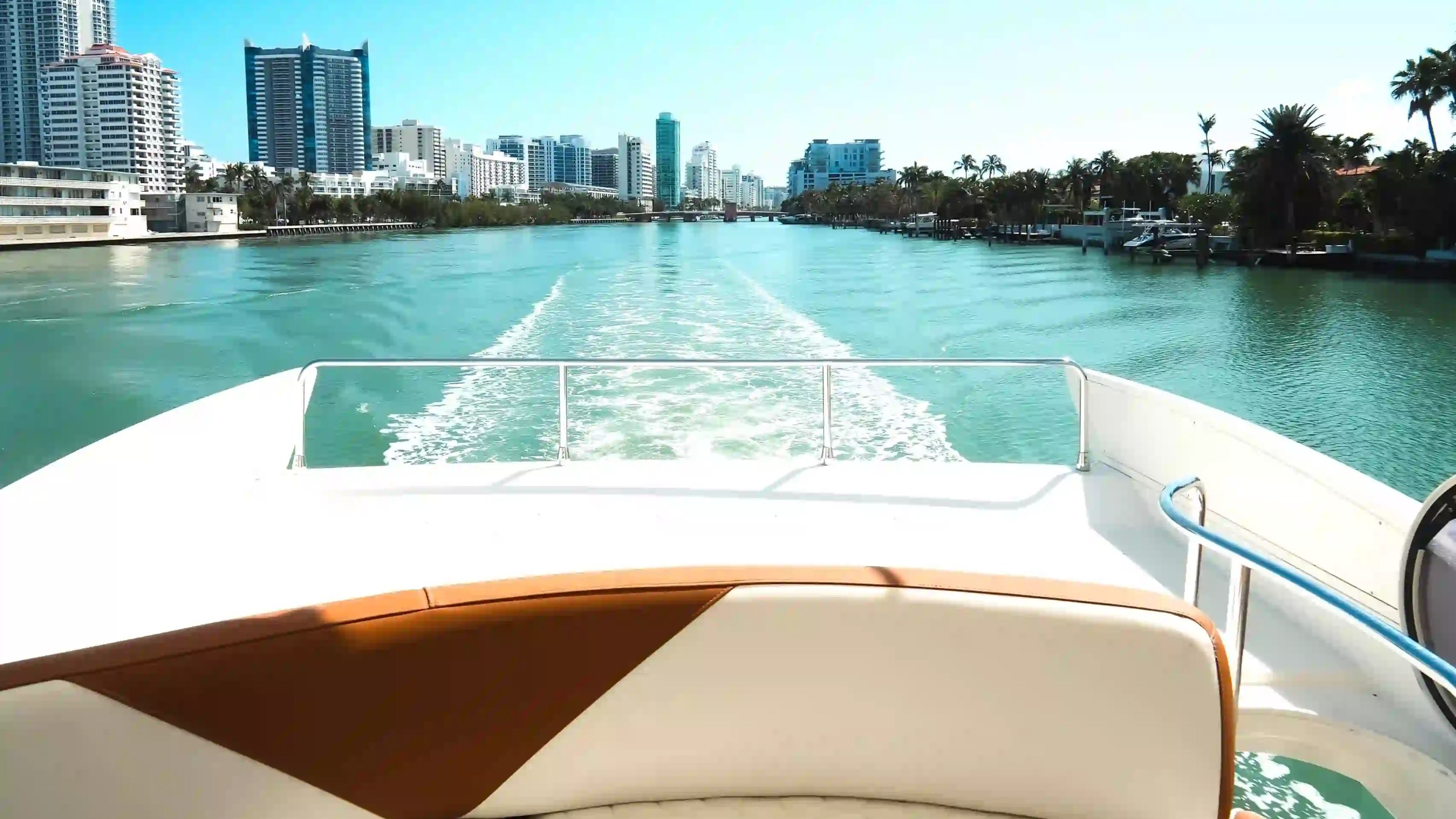 View from a boat's deck showing a city skyline and waterway on a sunny day.
