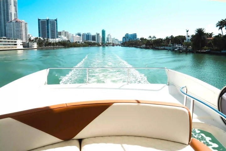 View from a boat's deck showing a city skyline and waterway on a sunny day.