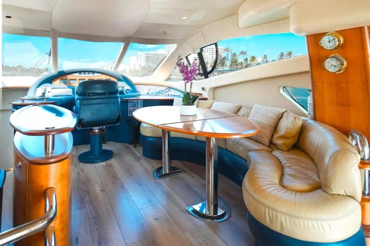 Luxurious yacht interior with leather seating, wooden table, and large windows with ocean view.