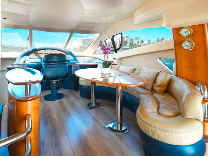 Luxurious yacht interior with leather seating, wooden table, and large windows with ocean view.