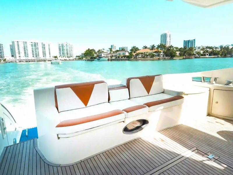 Boat deck with cushioned seating, city skyline and water view in background.