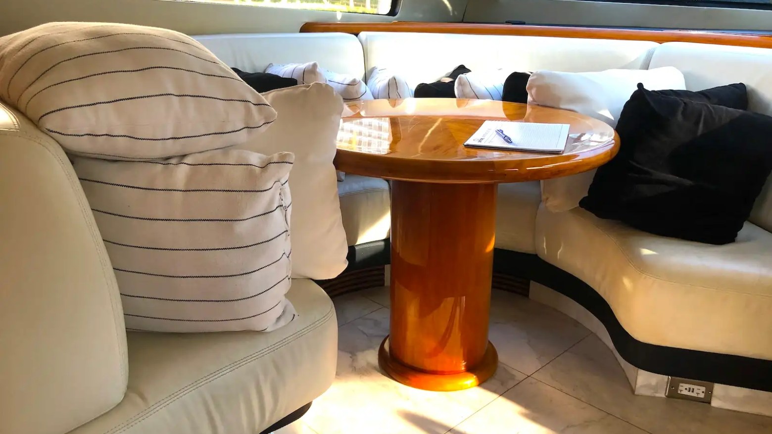 Luxurious yacht interior with a leather sofa, a wooden table, and striped cushions.