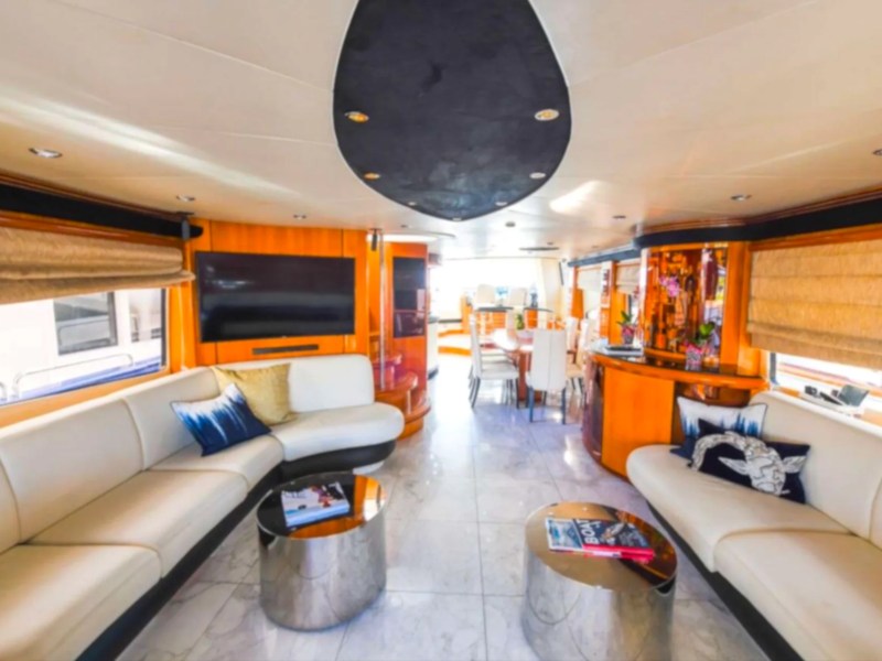 Luxurious yacht interior with leather sofas, TV, dining area, and modern decor.
