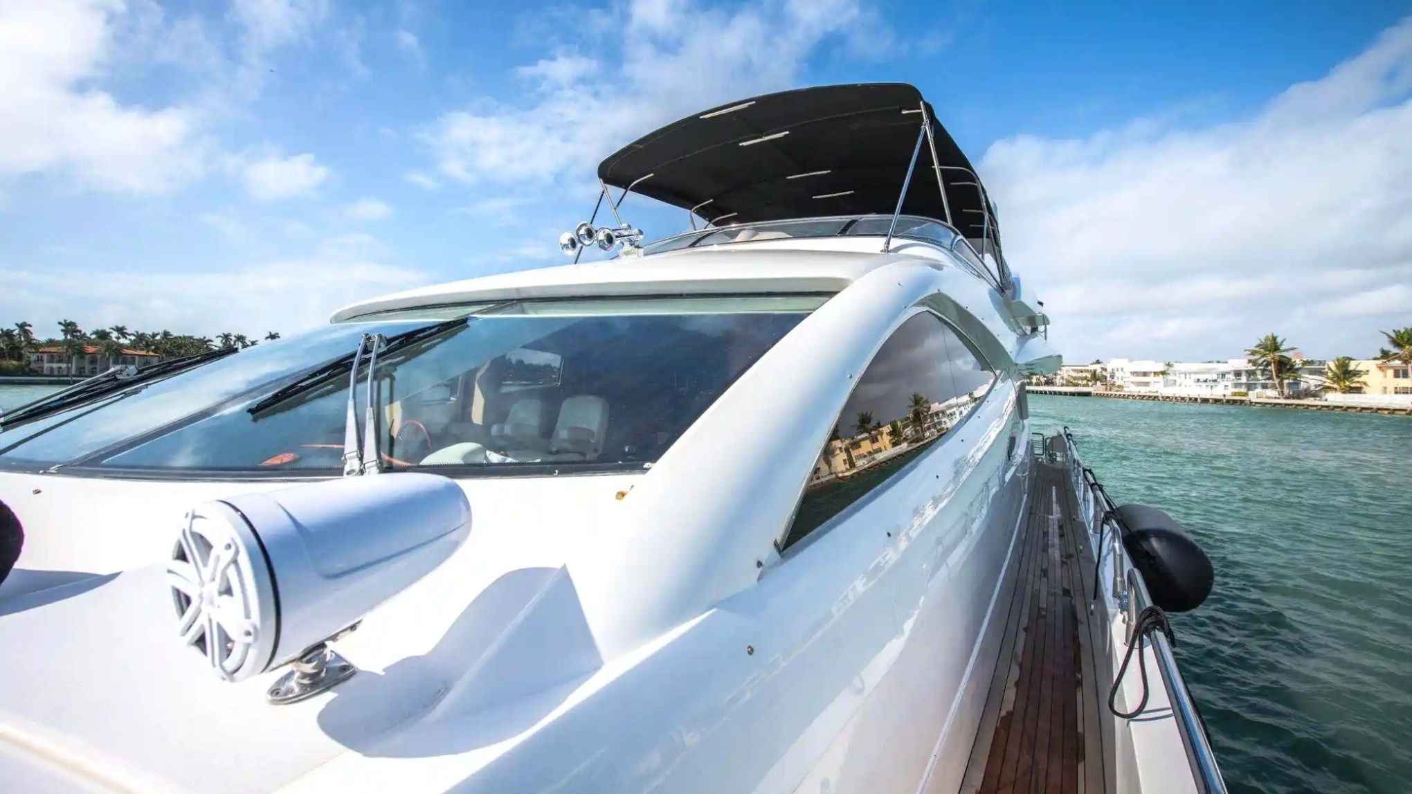 Luxury yacht on the water, clear sky, distant coastline with palm trees.