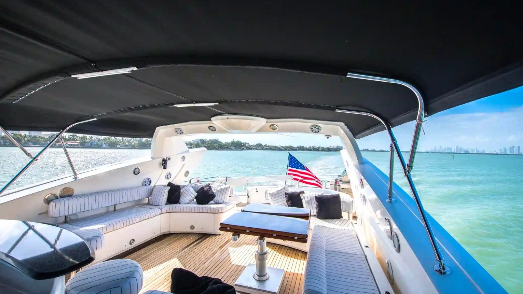 Spacious yacht deck with seating and American flag, overlooking a serene water view.