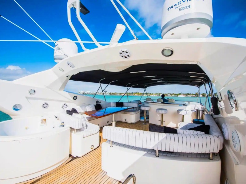 Luxury yacht deck with seating, bar stools, and ocean view under a clear blue sky.