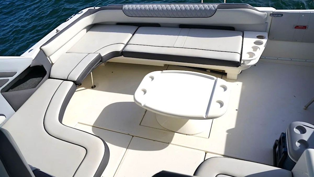 Top view of a boat's deck with curved seating and a central oval table.