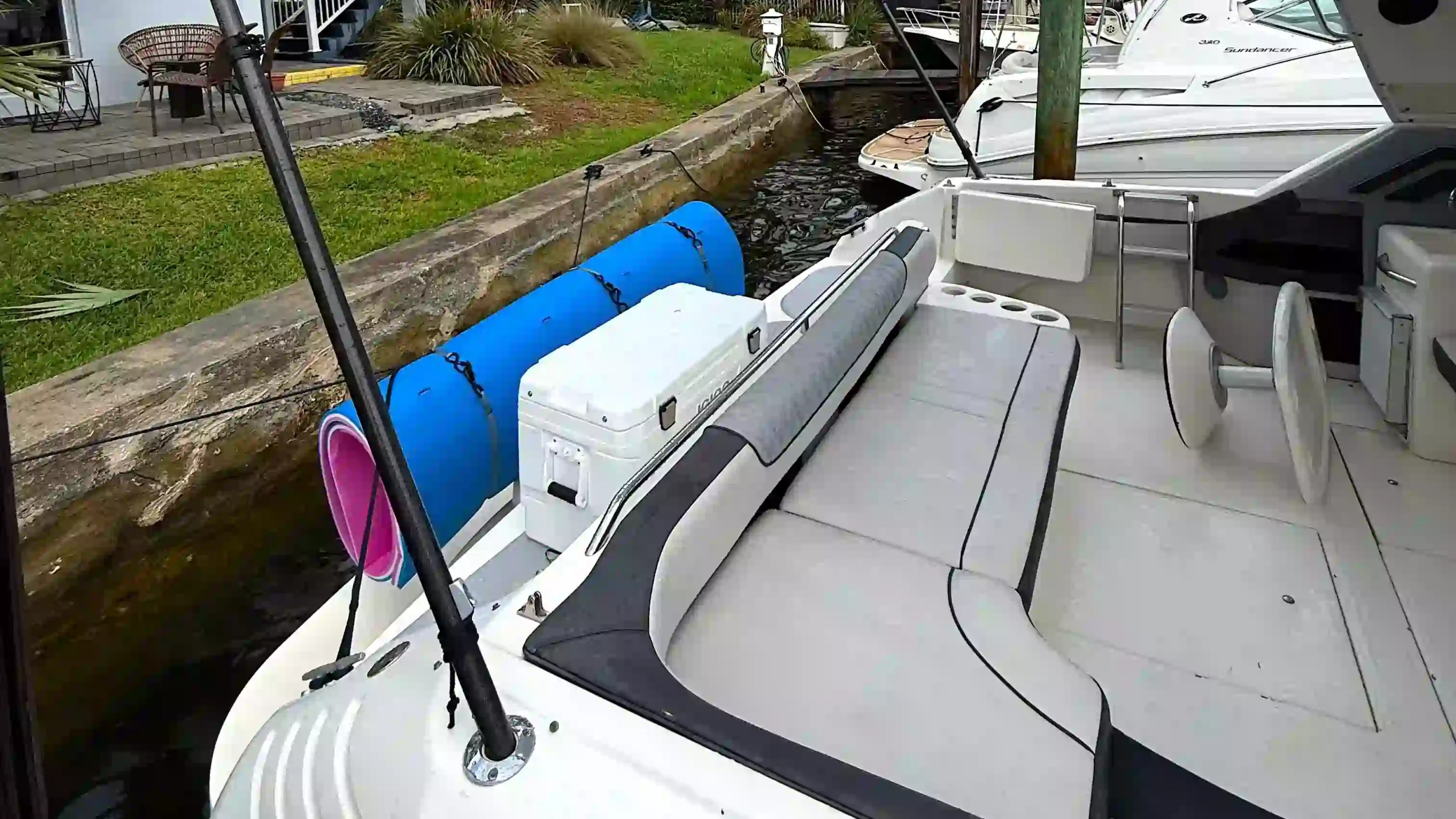 Deck of a docked boat with seating and a cooler nearby.