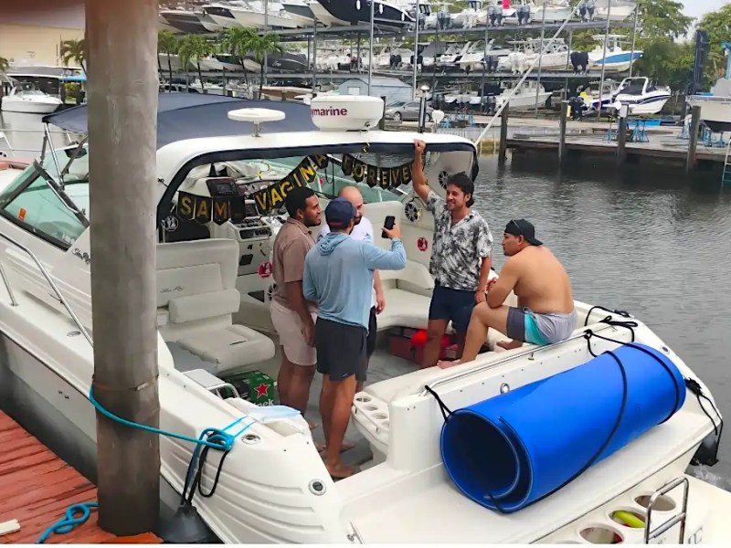 Group of people on a boat with festive decorations at a marina.
