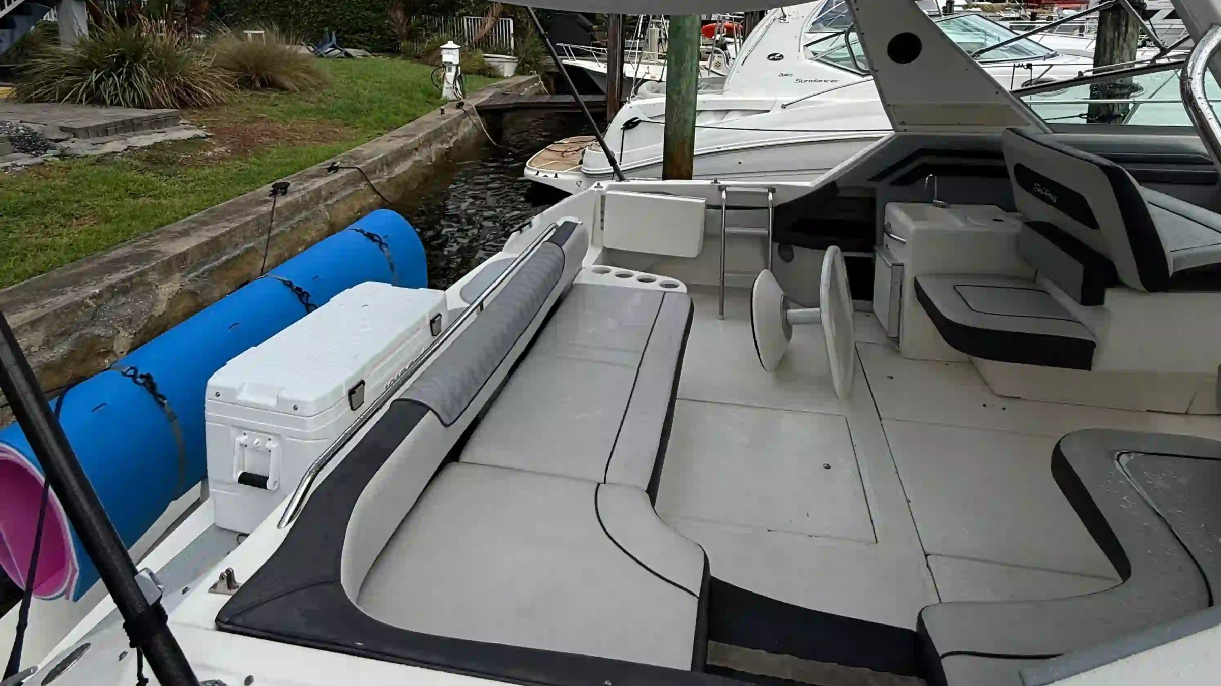 Empty boat deck with seating, canopy, and dockside view.