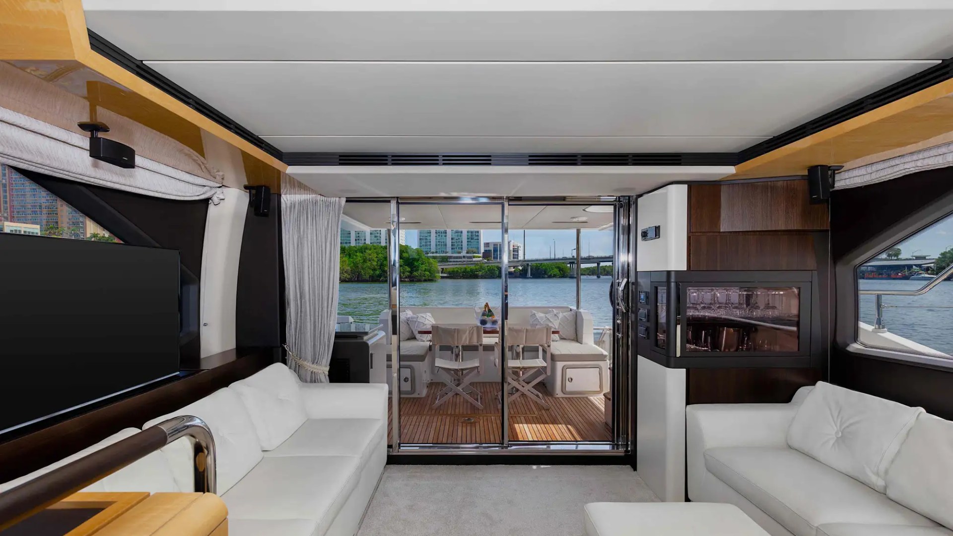 Luxurious yacht interior with sofas and view of water through open doors.