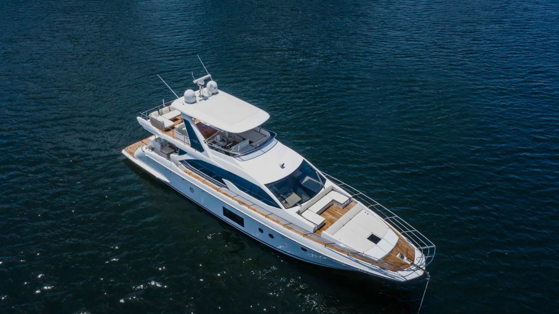 Aerial view of a white yacht with multiple decks on calm water.