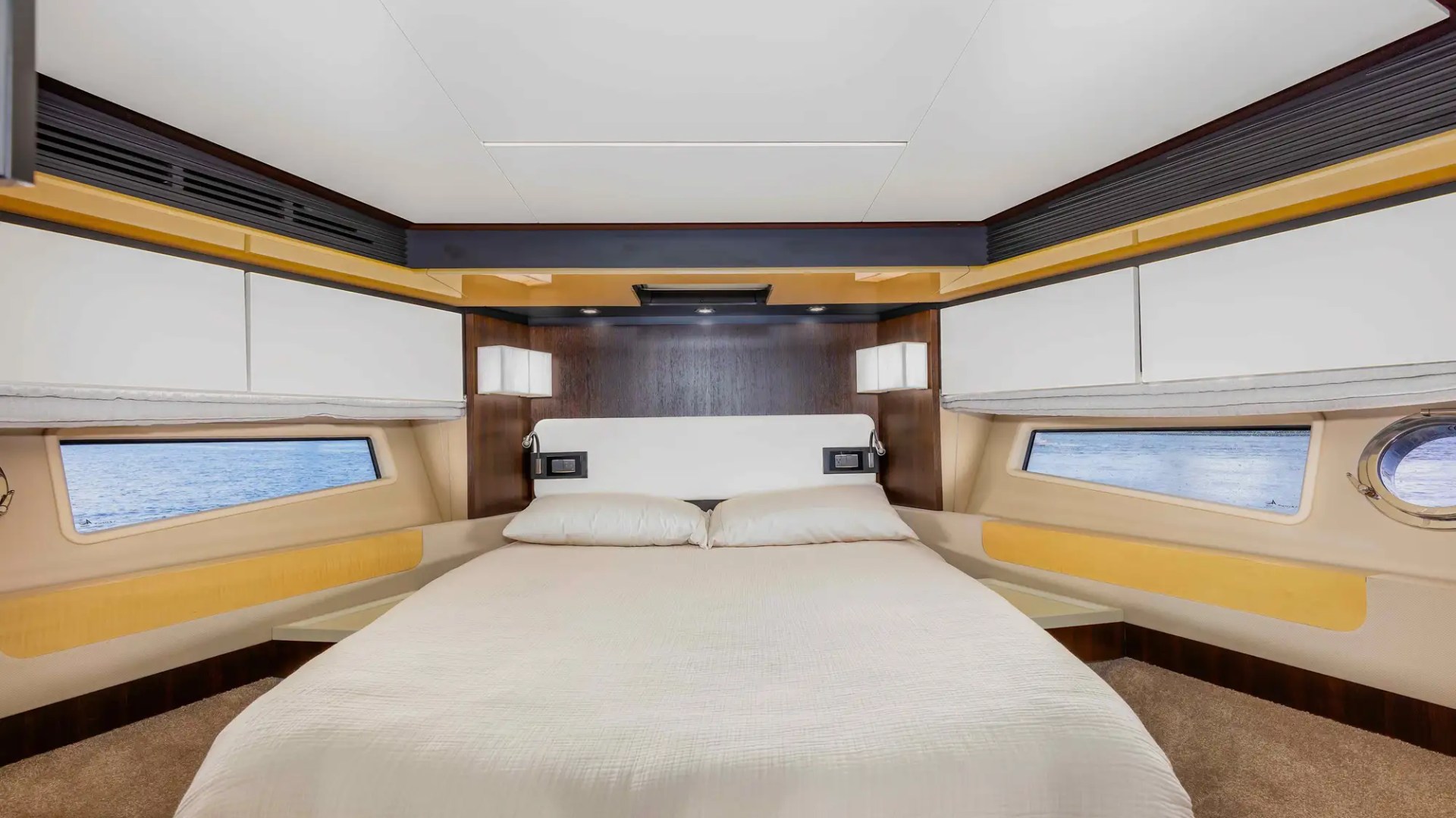 Modern yacht bedroom with a double bed and ocean view windows.