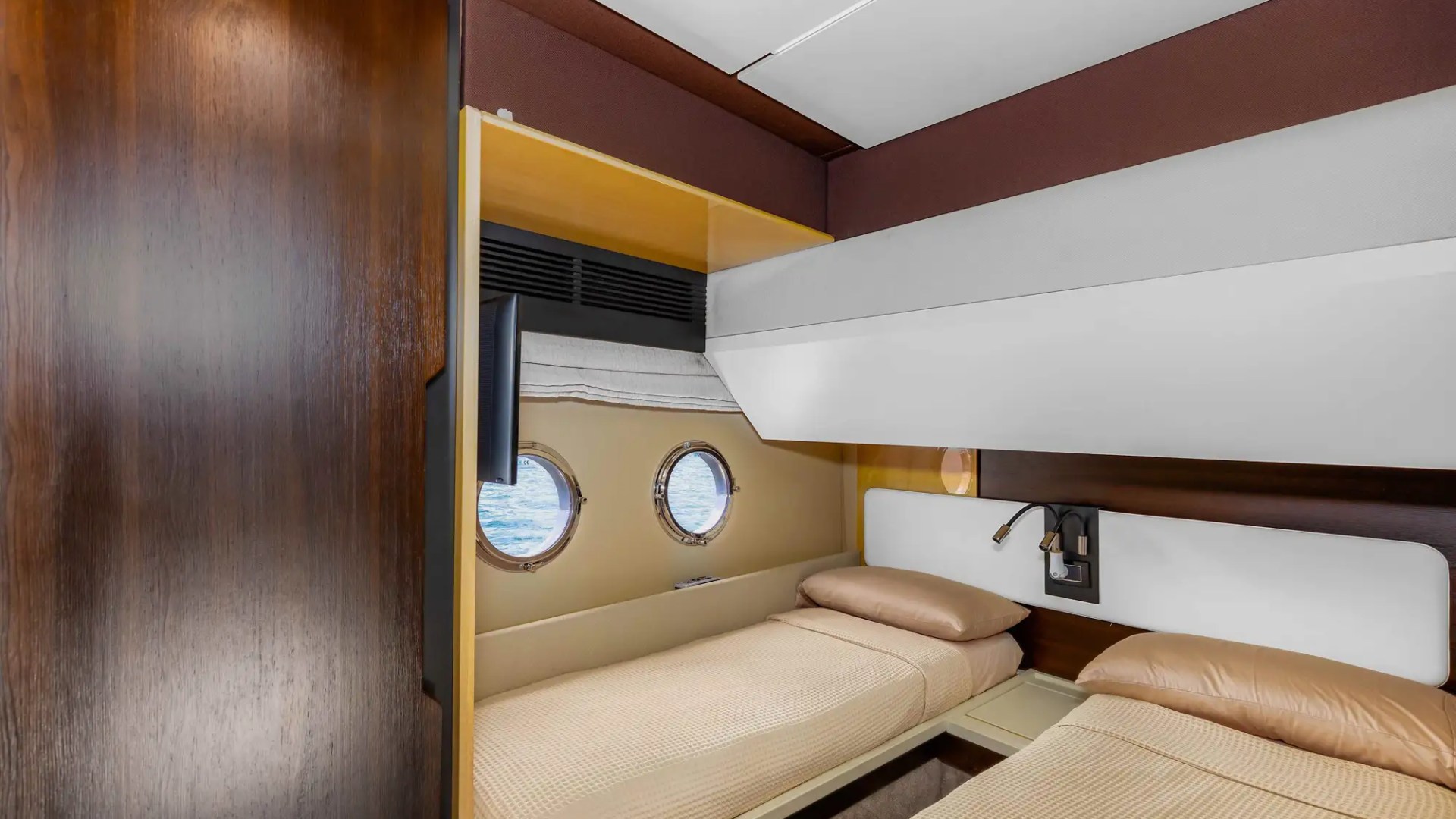 Small cabin with two single beds and round windows on a boat or yacht.
