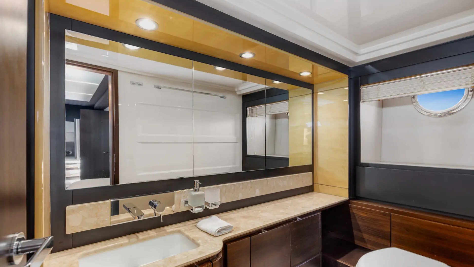 Modern bathroom with large mirror, sink, and circular porthole window.