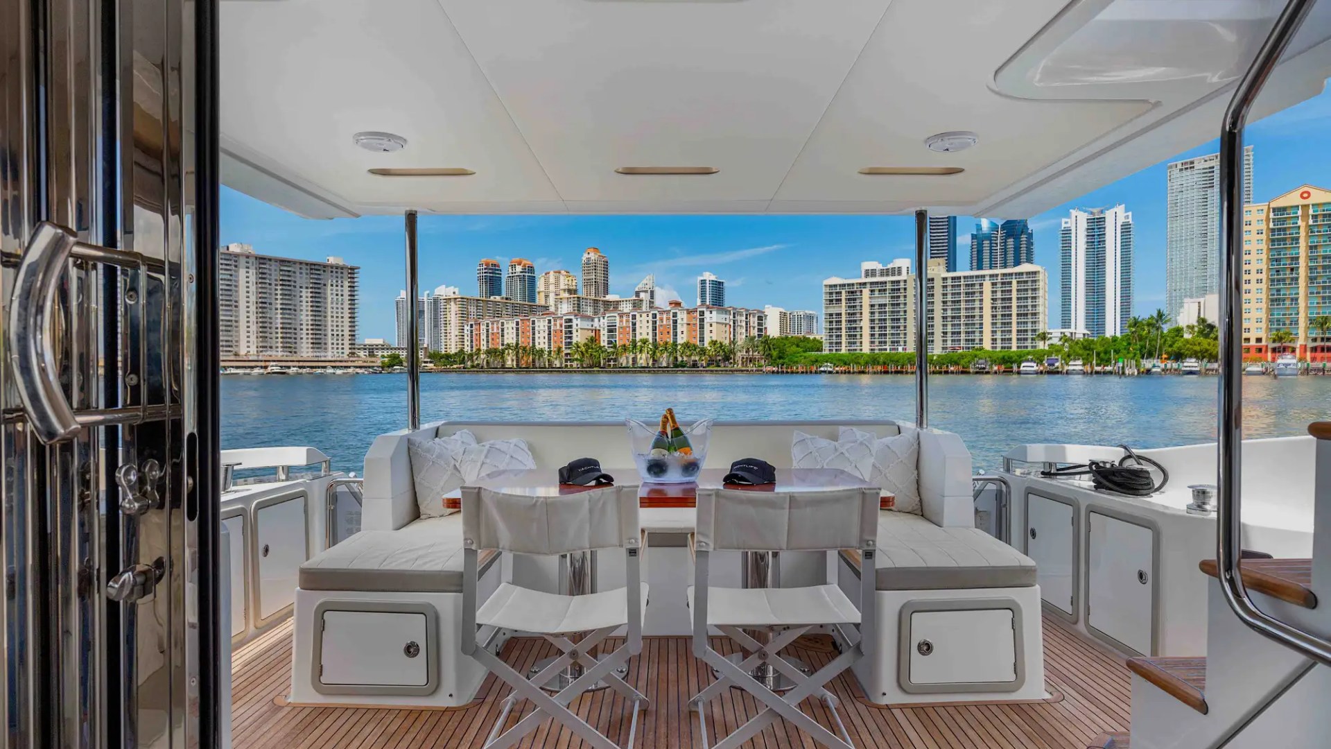 View of modern city skyline from a yacht deck with seating area.