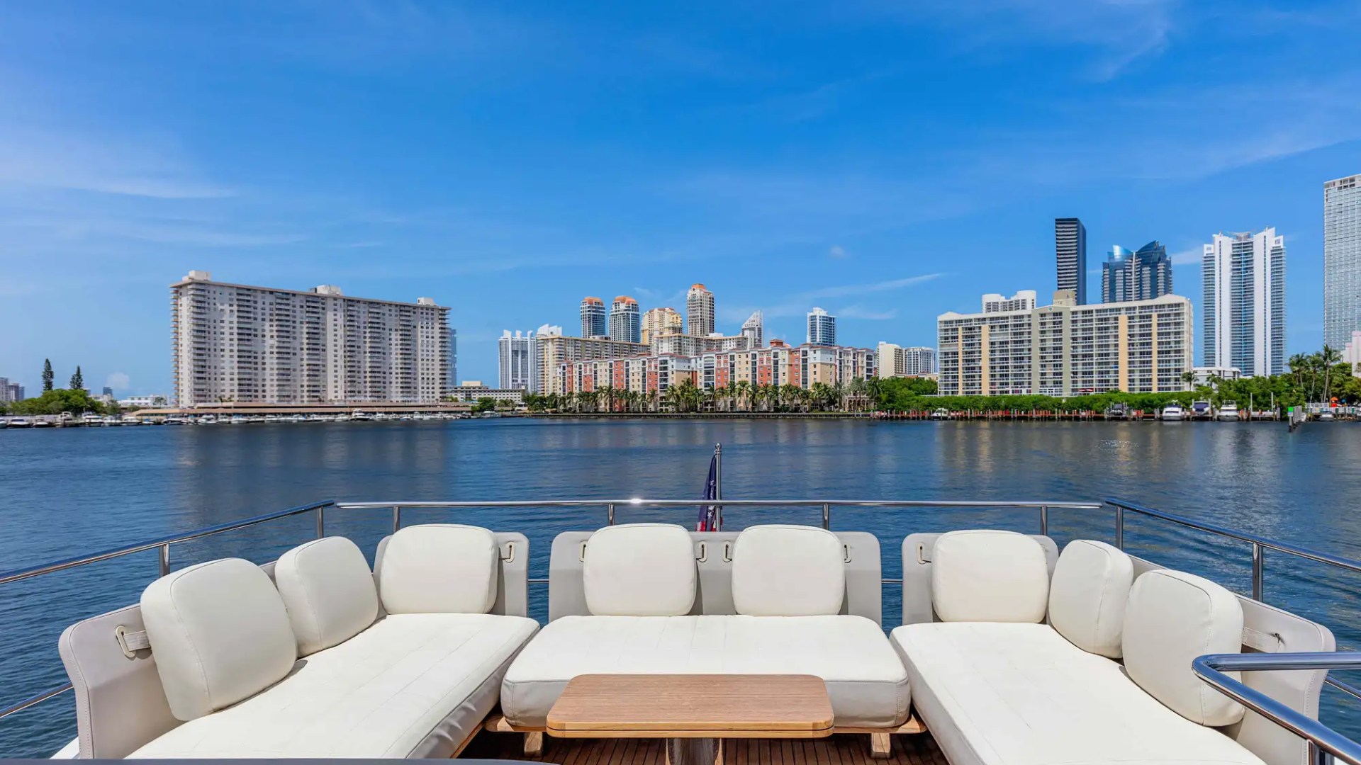 White sofa on yacht deck facing city skyline across the water.